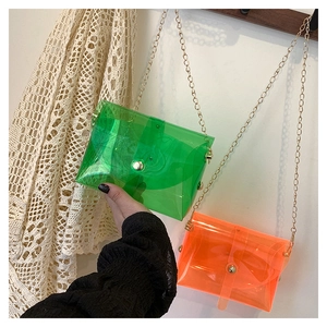 Detail of neon green and orange PVC crossbody bags with gold chain straps and metal buckles