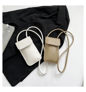 Detailopname van mini-crossbodytassen in wit en kaki met geweven structuur