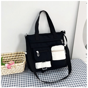 Detail of color-block canvas tote bag with functional pockets on a blue checkered tablecloth