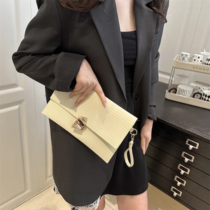 Cream striped envelope clutch with gold rotary lock and wrist strap held by model