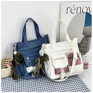Dettaglio di borse tote in tela multitasche con ciondoli a rana e design color-block