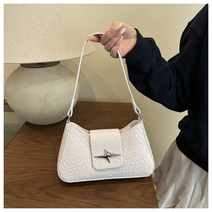 Detail of white woven shoulder bag with star metal buckle held in a cozy home setting