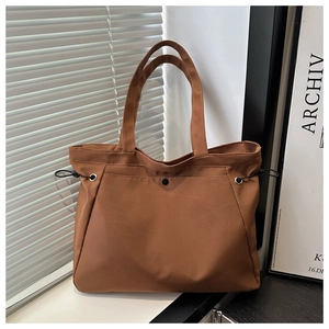 Detailed view of brown tote bag with drawstring sides and secure snap button pocket