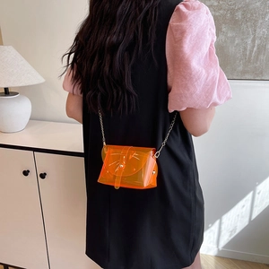 Minimalist orange transparent PVC crossbody bag with gold chain strap on model