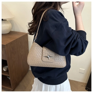 Detail of beige woven texture underarm bag with silver star buckle in a home setting