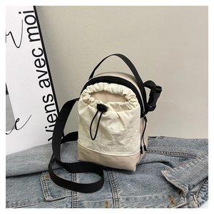 Detail of crossbody bag with beige fabric texture and black quick-release buckle