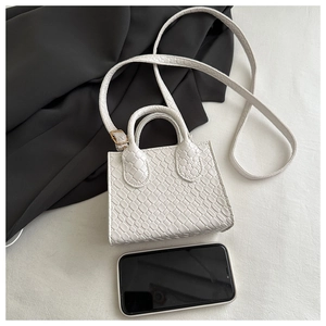 Top view of white mini woven handbag with adjustable strap and smartphone for size