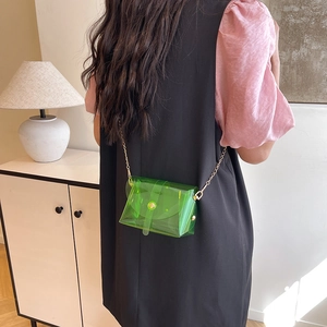 Transparent green PVC mini crossbody bag with gold chain strap worn by a model