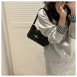 Detail of black faux crocodile leather shoulder bag with a silver star metal buckle