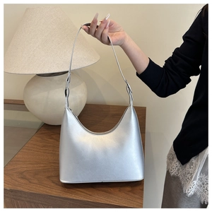 Close-up of a silver crescent-shaped underarm bag with metallic texture and sleek strap