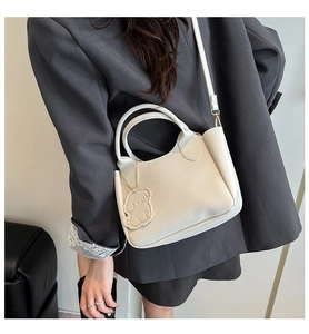 Détail du sac à main crème avec poignées rondes et pendentif mignon en forme de chien