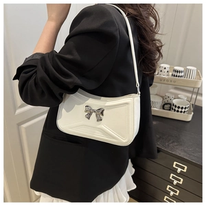 Detail of white shoulder bag with silver bow buckle and geometric embossed pattern