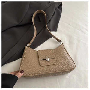 Macro view of khaki faux leather shoulder bag with crocodile texture and silver star charm