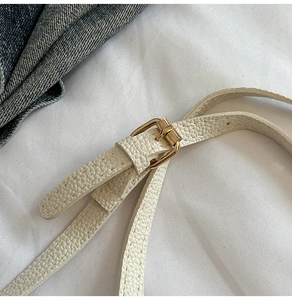 Détail de la bandoulière en cuir beige grainé avec boucle dorée pour sac seau