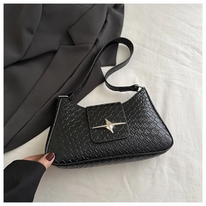 Close-up of woven texture on black underarm bag with silver star buckle detail