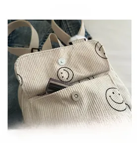 Detail of beige corduroy bag with smiley embroidery and magnetic metal closure