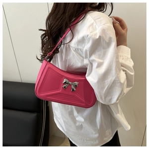 Close-up of bright magenta baguette bag with silver bow and geometric embossing details