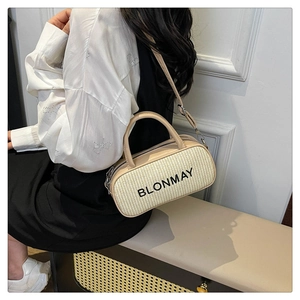 Detail view of woven beige baguette bag with BLONMAY lettering and adjustable strap