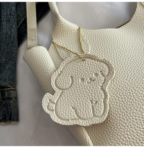 Détail d'un charmant chien blanc sur un sac cabas en cuir avec chaîne dorée