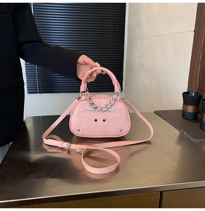 Dettaglio borsa rosa con trama a coccodrillo, borchie d'argento e catena decorativa