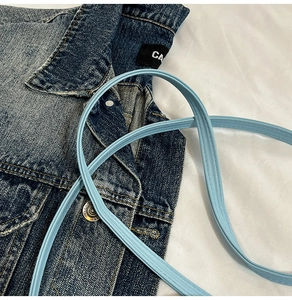 Macro shot of light blue faux leather bucket bag strap with reinforced stitching details