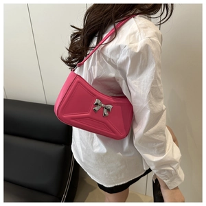 Detail of fuchsia shoulder bag with 3D quilted texture and silver bow metallic buckle