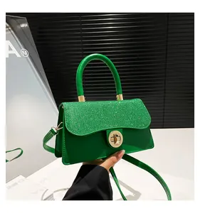 Detail of green sequin handbag with gold metal clasp and cylindrical top handle