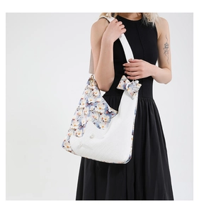 Detail of floral patchwork tote bag featuring pearl accents and a decorative ribbon bow