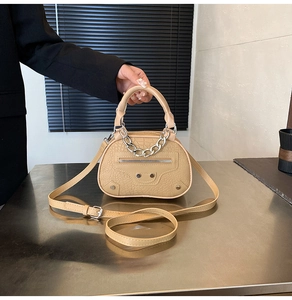 Dettaglio borsa a mano beige effetto coccodrillo con catena argento e borchie
