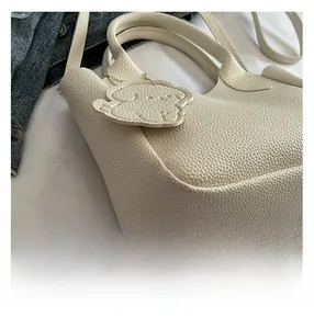 Détail du sac seau en cuir litchi blanc cassé avec breloque chien et chaîne dorée