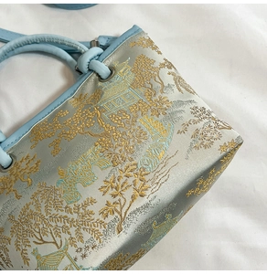 Detail of light blue silk bucket bag with gold Chinese garden and willow embroidery