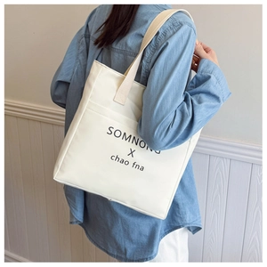 Detail view of large canvas tote bag featuring front pocket and printed lettering