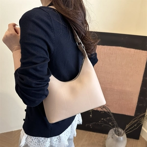 Minimalist beige crescent hobo shoulder bag shown on a model with an adjustable leather strap