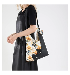 Close-up of black textured tote bag with yellow floral print and elegant pearl accents