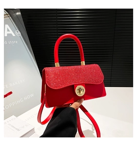 Detail of red sequin handbag featuring a gold circular twist lock and firm top handle