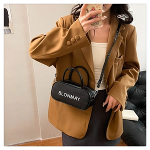 Detailed view of black woven pillow bag with white BLONMAY lettering and adjustable strap