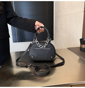 Dettaglio borsa a mano nera in pelle goffrata coccodrillo con borchie e catena d'argento