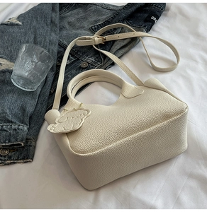Détail du sac seau blanc cassé avec texture cuir grainé et charmant pendentif mouton