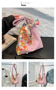 Close-up of pink woven tote bag with floral print, 3D bow, and pearl details