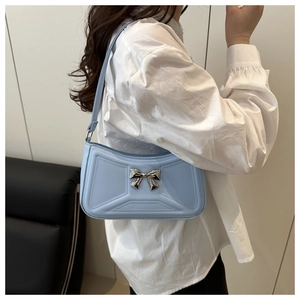 Detail of light blue shoulder bag with silver bow and geometric embossed pattern