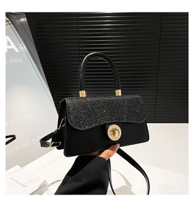 Close-up of black handbag featuring starry sequin flap and golden round twist lock