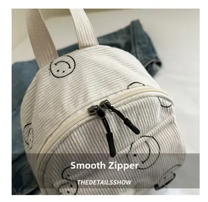 Detail of smooth double zippers and corduroy texture on the white smiley backpack
