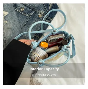 Internal capacity of light blue leather handbag with golden floral embroidery and tassels