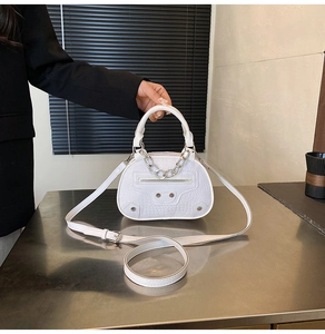 Dettaglio borsa bianca con motivo coccodrillo, borchie argento e nappine in pelle