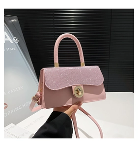 Detail of light pink handbag featuring rhinestone flap and golden twist lock closure