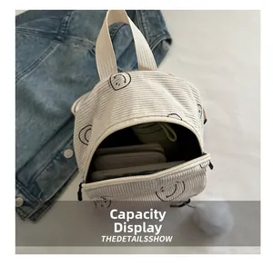 Interior capacity display of off-white corduroy backpack showing daily essentials and smile logo