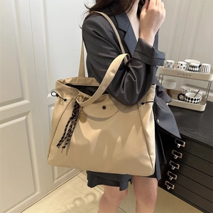 Large beige nylon tote bag for women with drawstring detail and round charm pendant