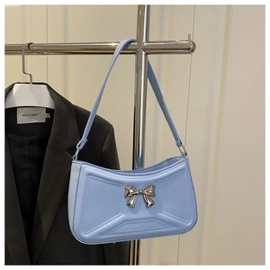 Detail of light blue shoulder bag with 3D X-stitching and silver metal bow ornament