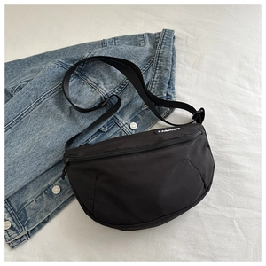 Détail du sac croissant en nylon noir avec étiquette Fashion sur fond de jean bleu
