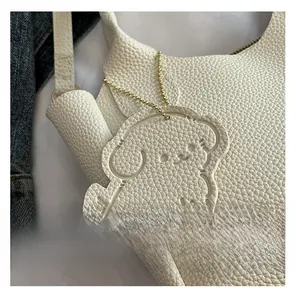 Détail du sac à main blanc en cuir grainé avec un charmant pendentif chiot et métal doré